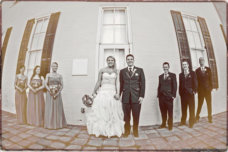 Bride and groom posing with wedding party during outdoor wedding portraits