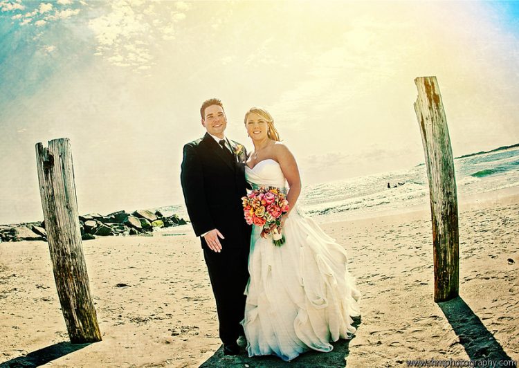 Bride and groom posing together on sunny beach during seaside wedding portrait session