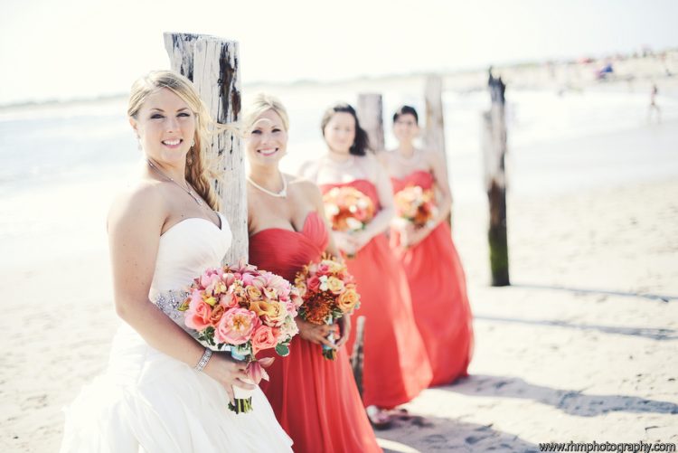 Bride and bridesmaids posing together on sunny beach during seaside wedding portrait session