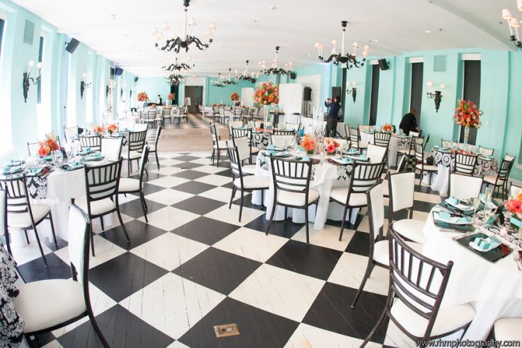 Elegant wedding reception hall with decorated tables, floral centerpieces, and checkered dance floor
