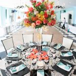 Wedding reception table centerpiece with vibrant floral arrangement and elegant place settings