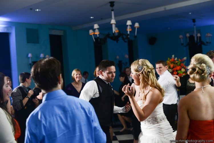 Bride and groom dancing together with guests during lively wedding reception celebration