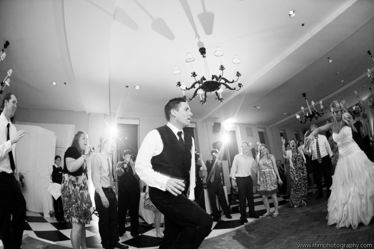 Bride and groom dancing with guests gathered around during lively wedding reception celebration