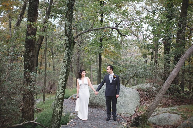 Bride and groom holding hands on wooded path