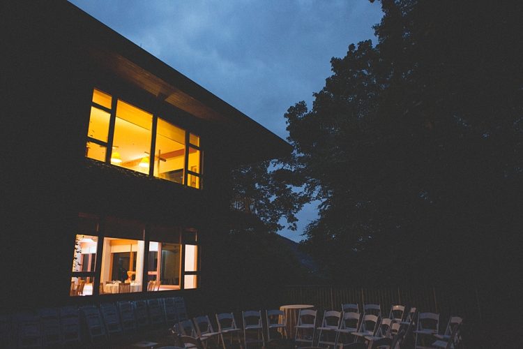 Outdoor wedding ceremony setup with chairs beside modern house at dusk