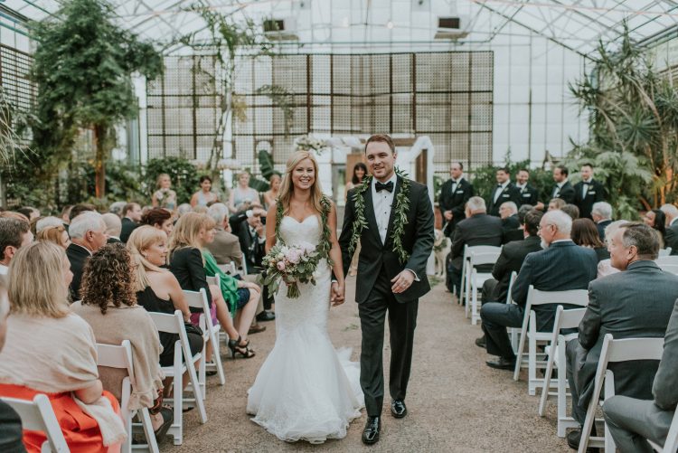 Bride and groom walking down aisle after ceremony in greenhouse wedding venue