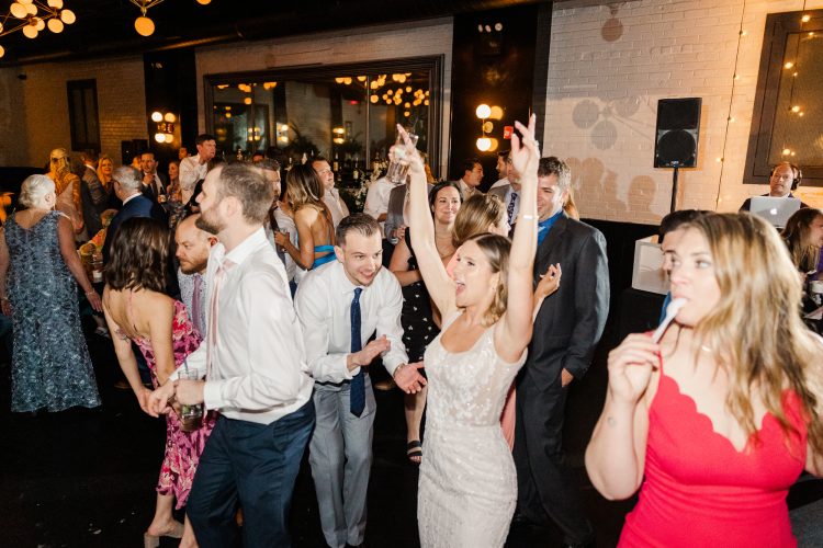 Bride celebrating with wedding guests on lively reception dance floor