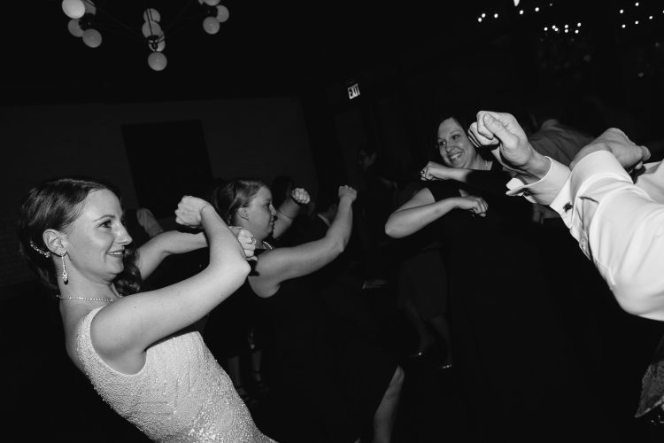Bride and guests dancing playfully on dark reception dance floor