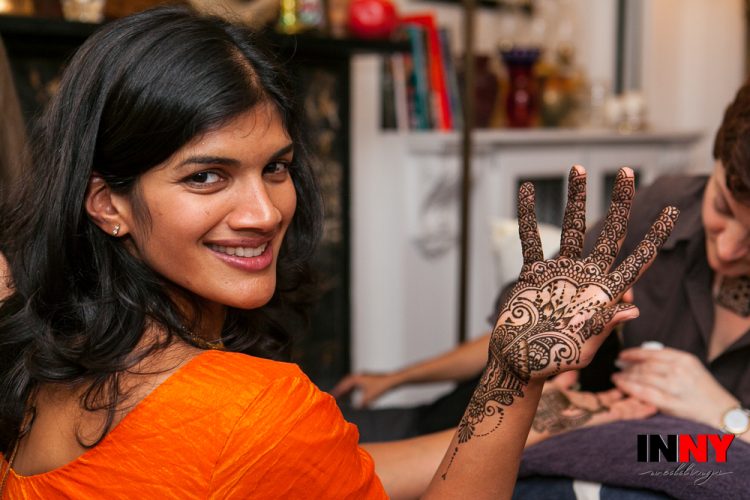Woman smiling while showing intricate henna design on her hand