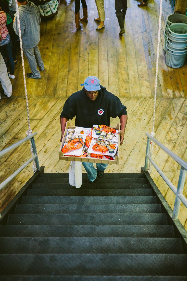 Man carrying trays of seafood up stairs in indoor market