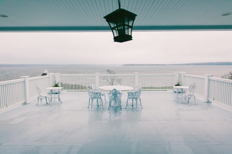Covered patio with tables and chairs overlooking waterfront view