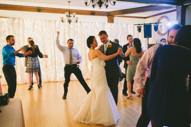 Bride and groom dancing together on reception dance floor with guests