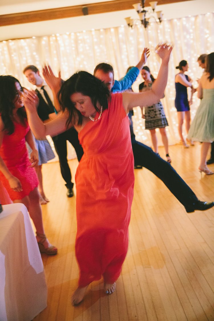 Guest dancing energetically on reception dance floor with others in background