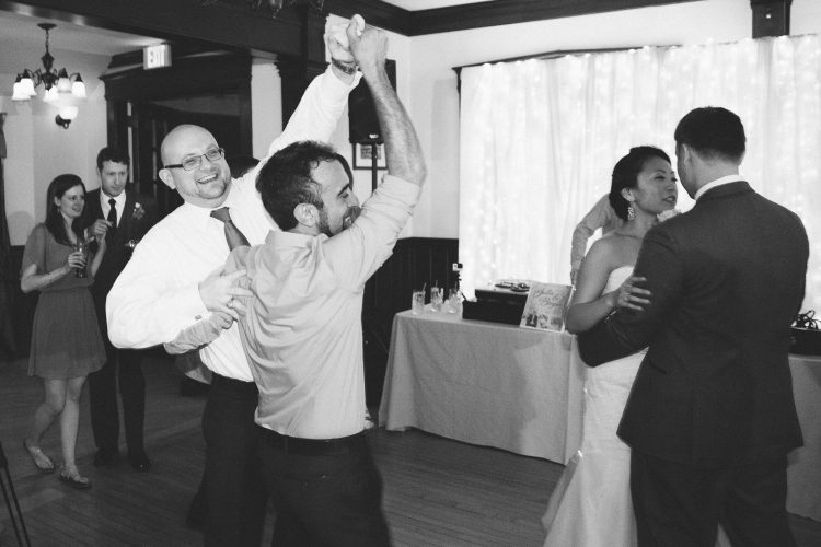 Guests dancing together on reception dance floor while couple dances nearby
