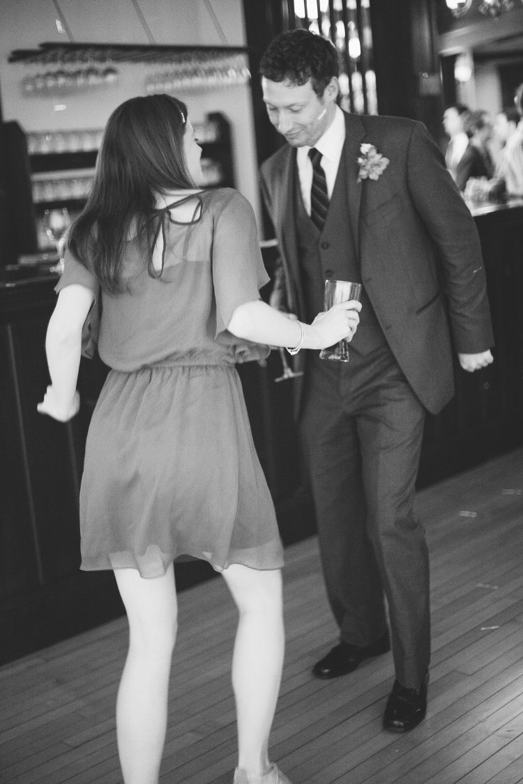 Man and woman dancing together while holding drinks at reception