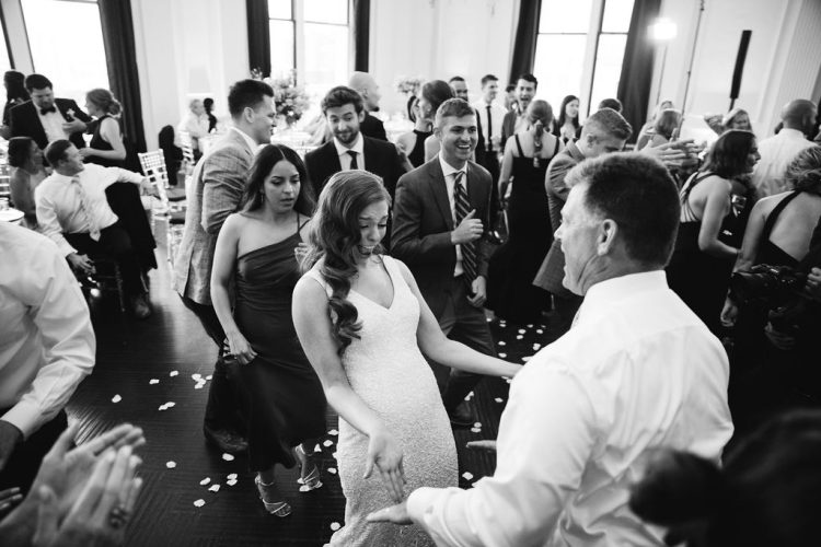 Bride dancing with guests on crowded reception dance floor