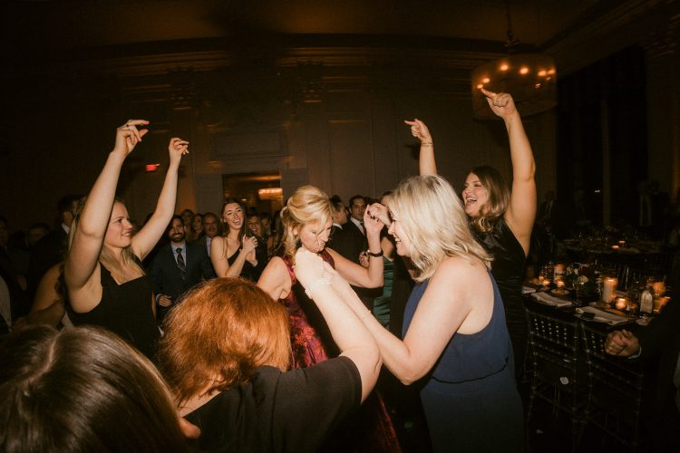 Guests dancing with raised hands on crowded reception dance floor