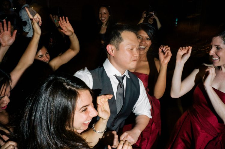 Guests dancing energetically together on crowded wedding reception dance floor during celebration