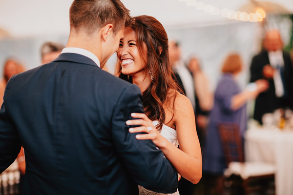 Bride smiling while dancing with groom during wedding reception celebration