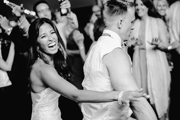 Bride laughing while dancing with guest during wedding reception celebration