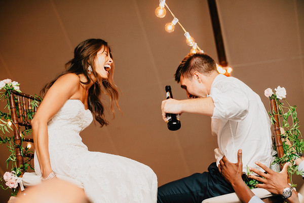 Bride and groom celebrating on chairs during lively wedding reception celebration