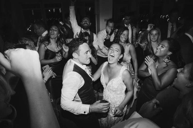 Bride and Groom singing along with guests on packed wedding dance floor.