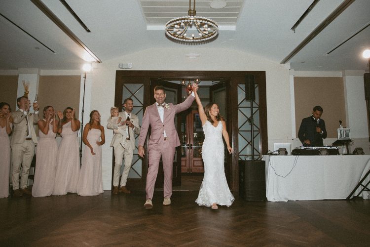 Bride and Groom making reception entrance while wedding DJ plays in background.