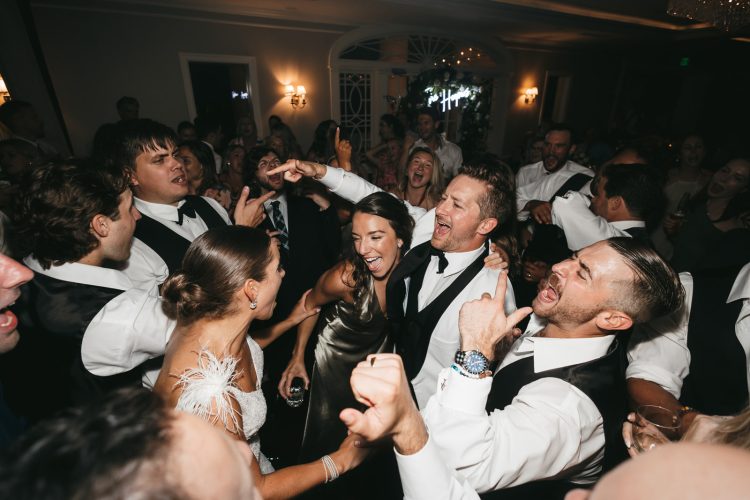 Wedding guests singing along together on crowded dance floor.