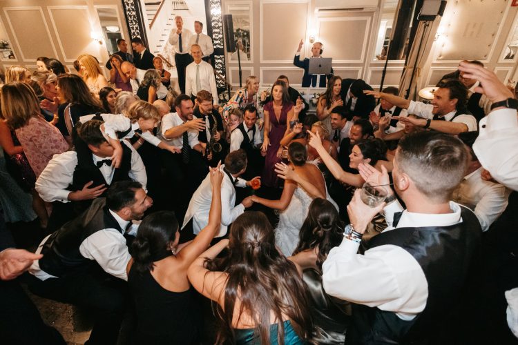 Bride and Groom surrounded by cheering guests in packed wedding dance floor.