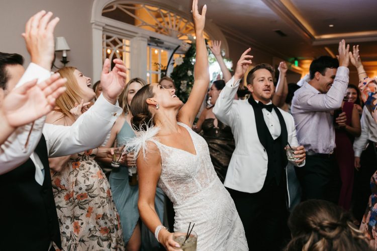 Bride and Groom singing along with guests on packed wedding dance floor.