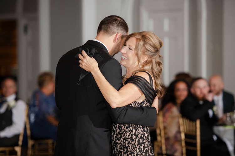 Groom sharing Mother-Son dance during wedding reception while guests watch.