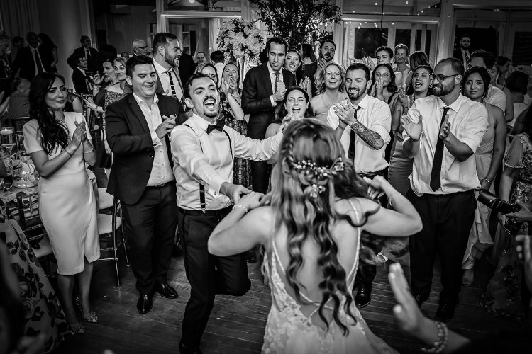 Bride and Groom dancing in circle of cheering guests on packed dance floor.