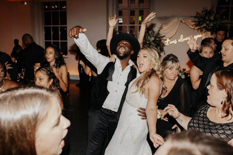 Bride and Groom dancing with guests while on crowded wedding dance floor.