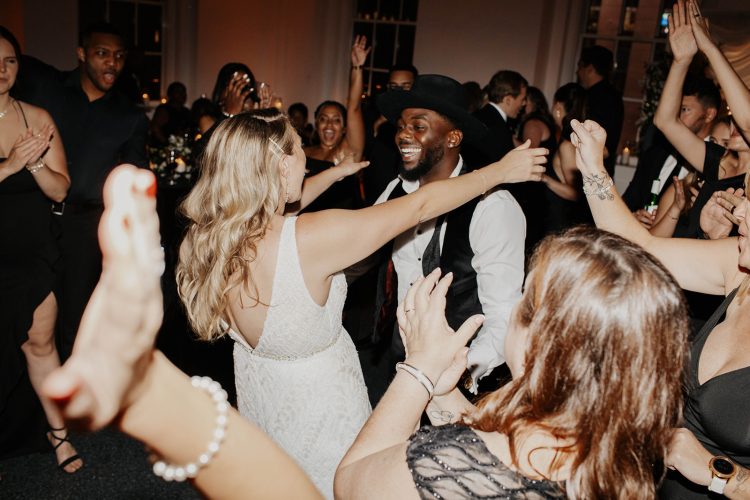 Bride & Groom with friends celebrate on crowded wedding dance floor.