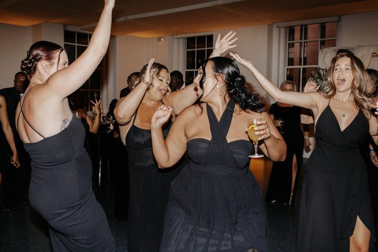 Wedding guests dancing together on crowded dance floor.