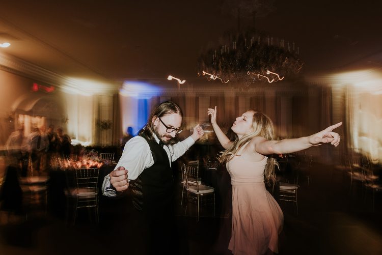 Wedding guests dancing together in elegant ballroom reception.