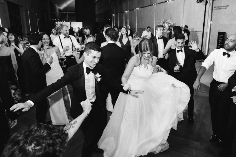 Bride and Groom dancing together surrounded by guests on crowded dance floor.