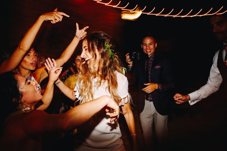 Bride dancing with friends during lively wedding dance floor moment.