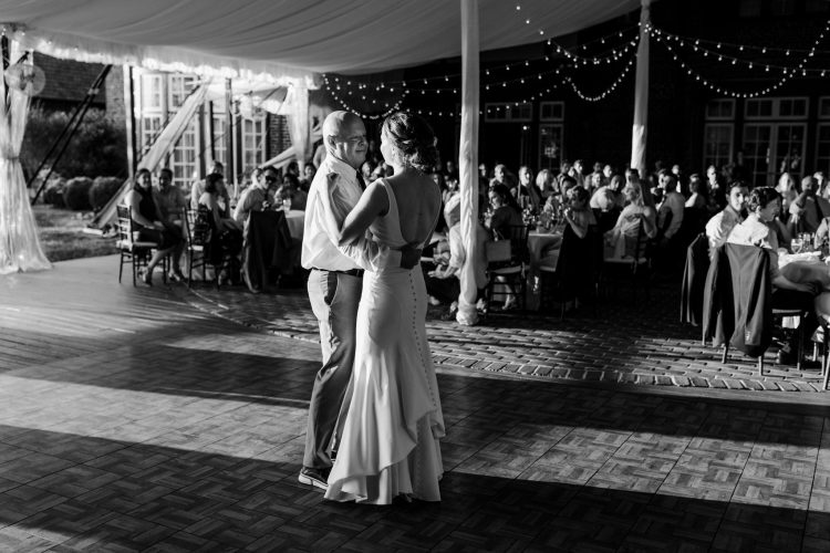 Bride sharing Father-Daughter dance under string lights at outdoor wedding.