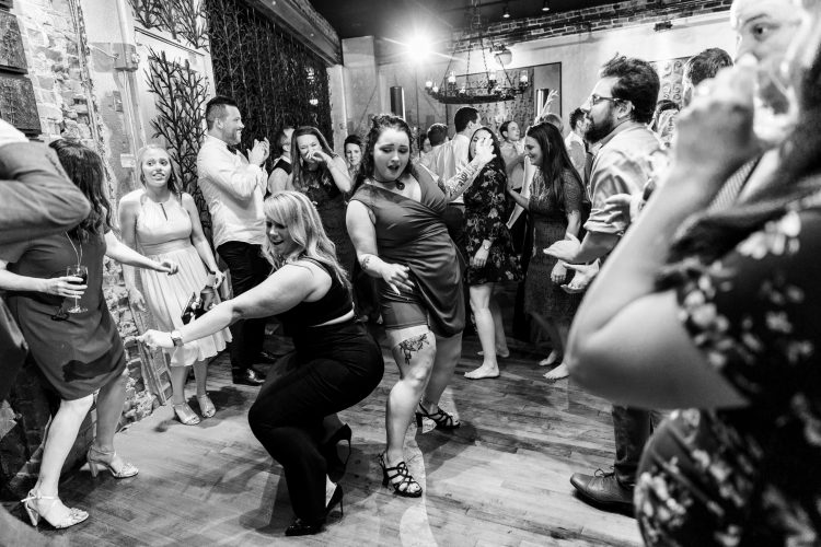 Wedding guests dancing together on crowded reception dance floor.