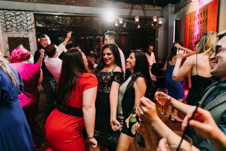 Wedding guests dancing together during lively reception dance floor moment.