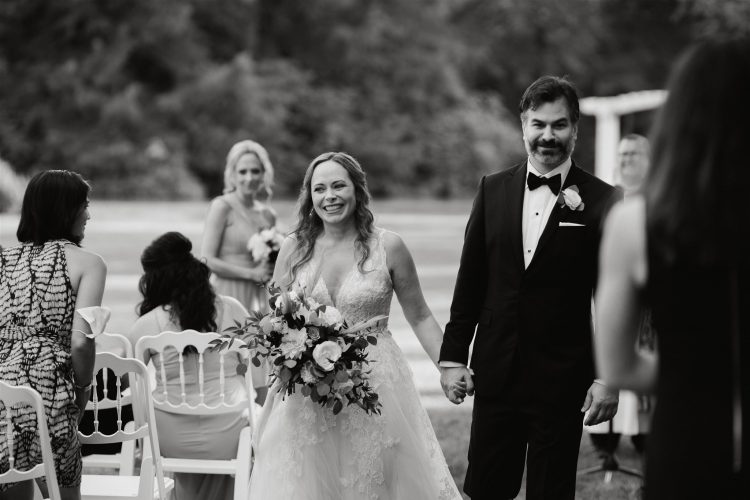 Bride and groom walking down aisle after outdoor wedding ceremony.