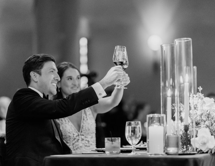 Bride and groom raising glasses during wedding reception toast.