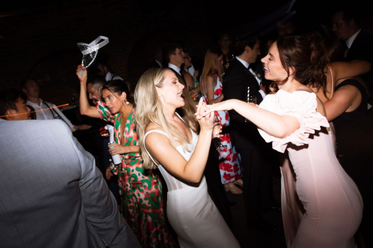 Wedding guests dancing together on crowded reception dance floor.