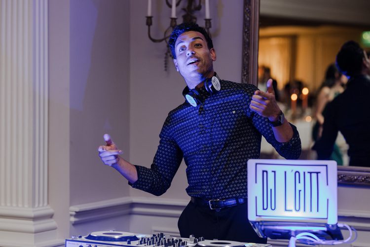 Wedding DJ performing behind DJ booth during reception.
