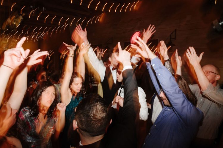 Guests raising their hands while dancing on the reception floor.