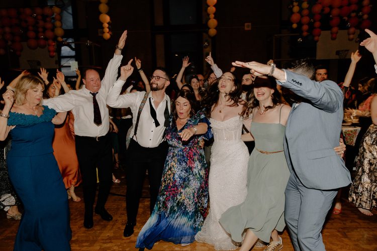Bride and guests dancing together on the reception floor.