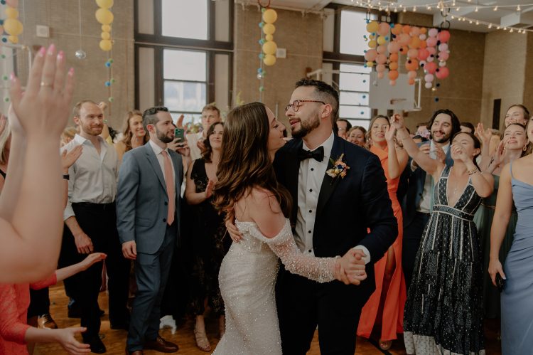 Bride and groom dancing surrounded by cheering guests.
