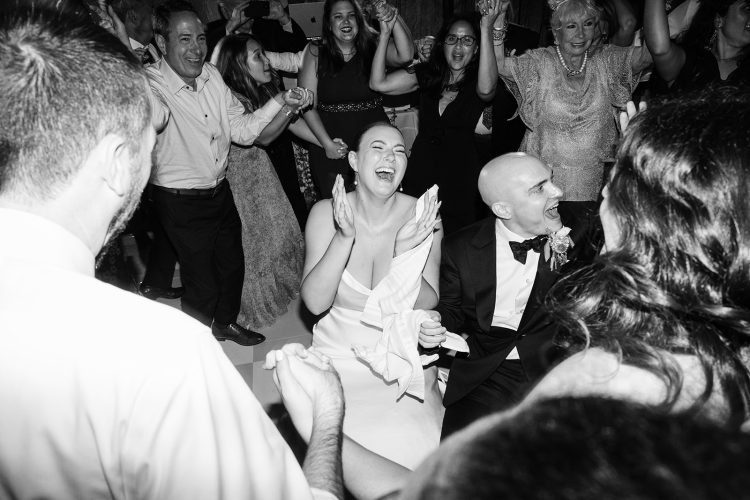 Bride and groom laughing with guests on the dance floor.