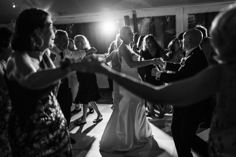 Bride dancing with guests in a circle on the dance floor.